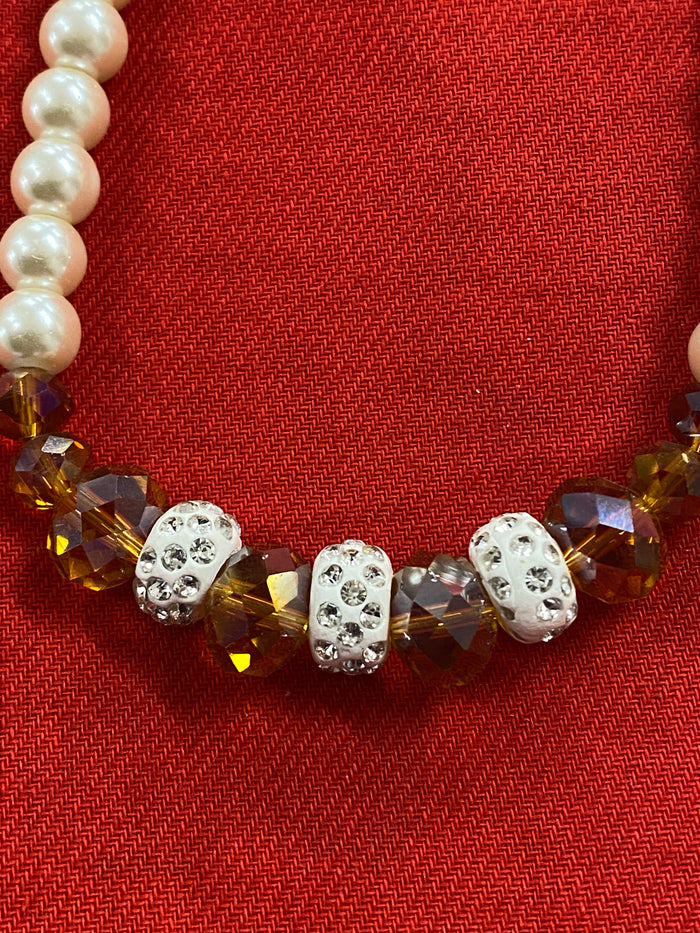 Vintage-Perlenkette, 55 cm lang, mit cremeweißen Perlen, funkelnden Kristallakzenten und weißen Strass-Zwischenelementen auf rotem Hintergrund.