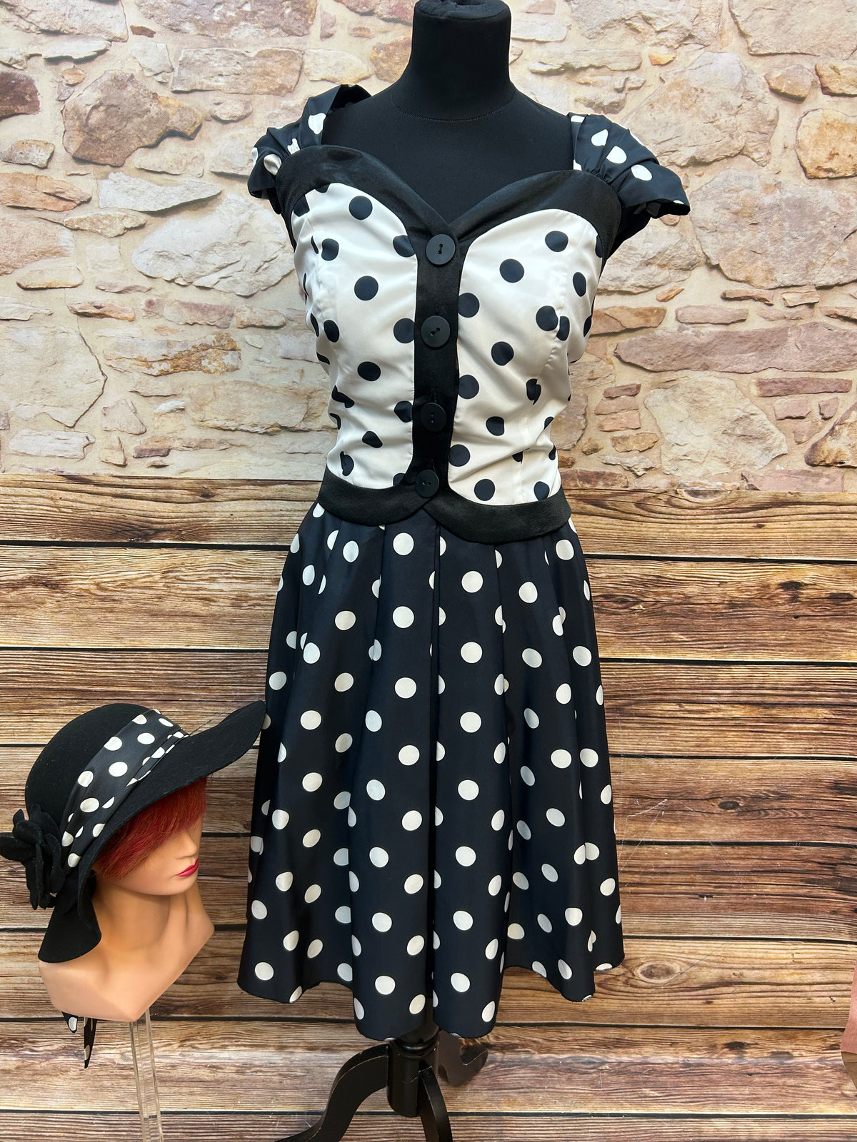 Vintage Damen-Punkte-Set: schwarz-weiß getupftes Oberteil mit Knöpfen und ausgestelltem Rock, schwarze Satinhandschuhe und schwarzer Filz-Cloche-Hut mit Punkte-Schleife