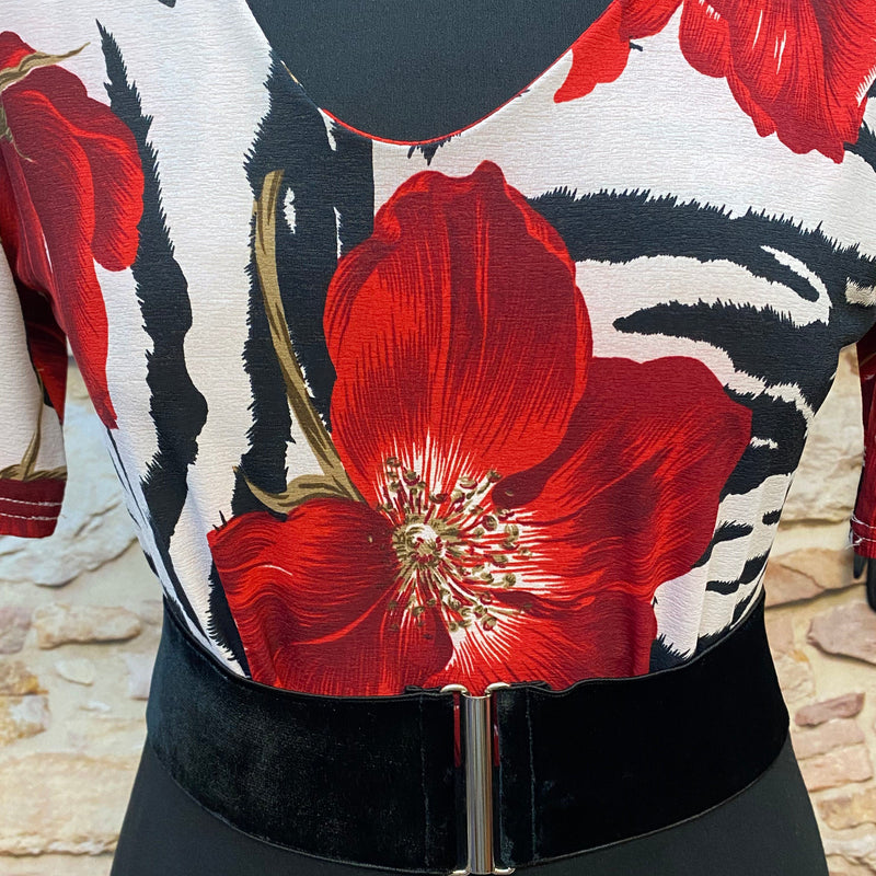 „Detailaufnahme Rockabilly Oberteil mit großer roter Blume, schwarz-weißem Muster und schwarzem Samtgürtel“