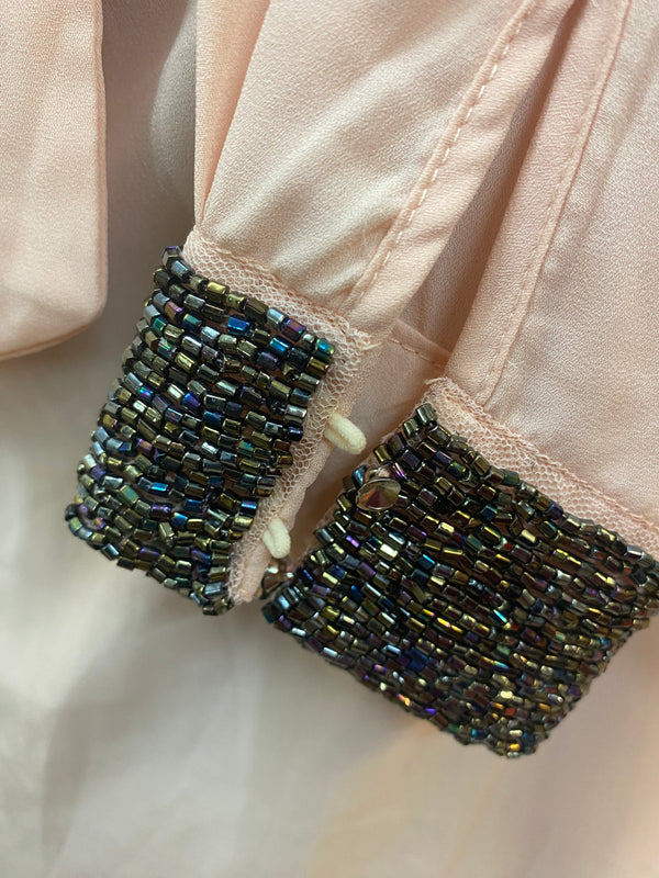 „Detailaufnahme Vintage Schluppenbluse mit funkelnden Perlen an den Manschetten“