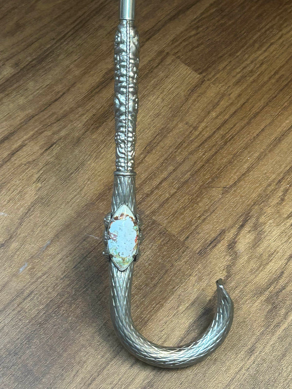 „Detailaufnahme silberfarbener Griff des Vintage-Schirms mit Relief und Emaille-Einsatz“