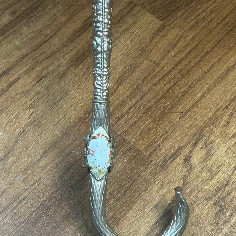 „Detailaufnahme silberfarbener Griff des Vintage-Schirms mit Relief und Emaille-Einsatz“