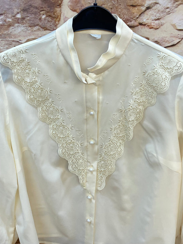 „Detailaufnahme der cremeweißen Vintage Bluse mit floraler Spitze und Knopfleiste“