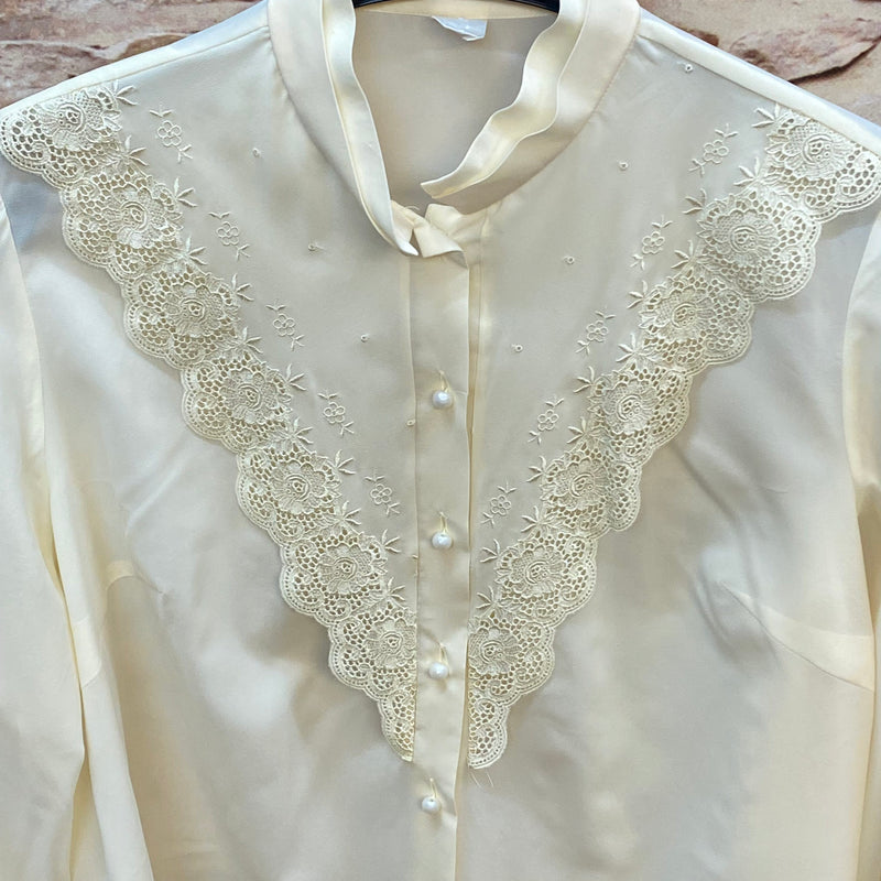 „Detailaufnahme der cremeweißen Vintage Bluse mit floraler Spitze und Knopfleiste“
