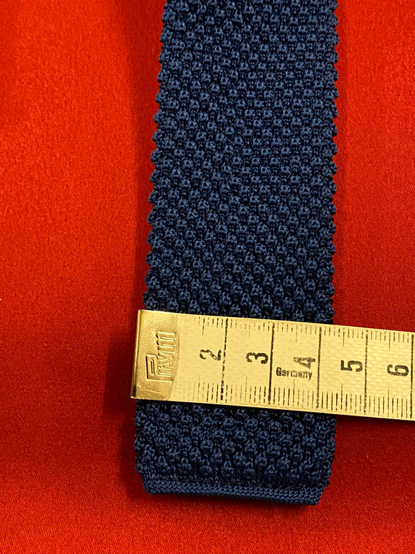 „Schmale Retro Strickkrawatte blau flach ausgelegt mit Maßband“
