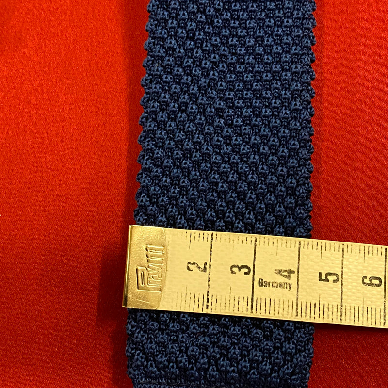 „Schmale Retro Strickkrawatte blau flach ausgelegt mit Maßband“