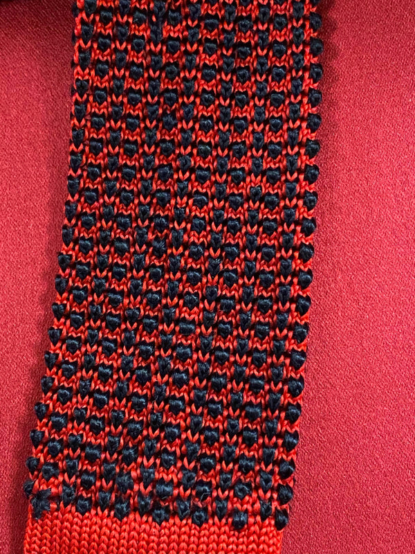 „Vintage Strickkrawatte rot schwarz aus Seide mit auffälligem Muster auf rotem Hintergrund“