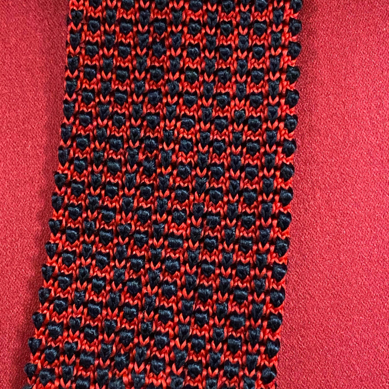 „Vintage Strickkrawatte rot schwarz aus Seide mit auffälligem Muster auf rotem Hintergrund“