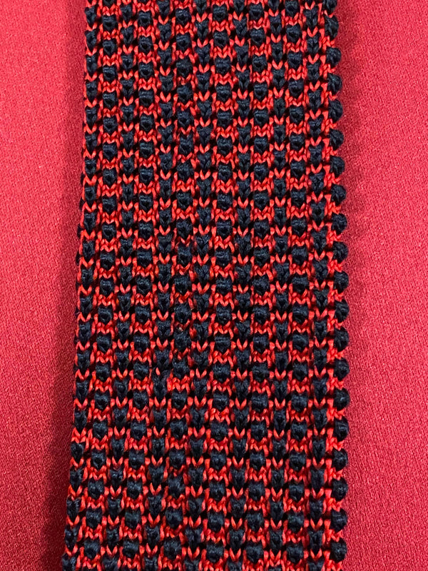 „Detailaufnahme gemusterte Strickkrawatte rot schwarz mit strukturierter Oberfläche“