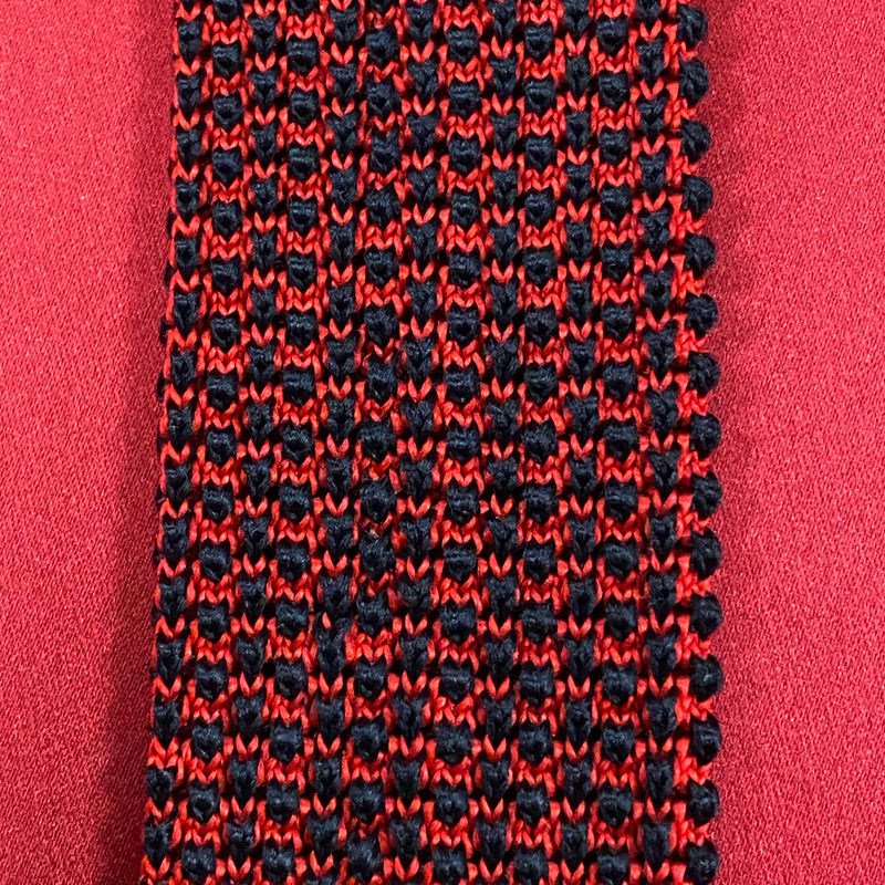 „Detailaufnahme gemusterte Strickkrawatte rot schwarz mit strukturierter Oberfläche“