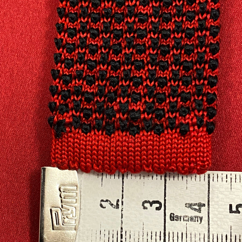 „Detailaufnahme gemusterte Strickkrawatte rot schwarz mit Massband“
