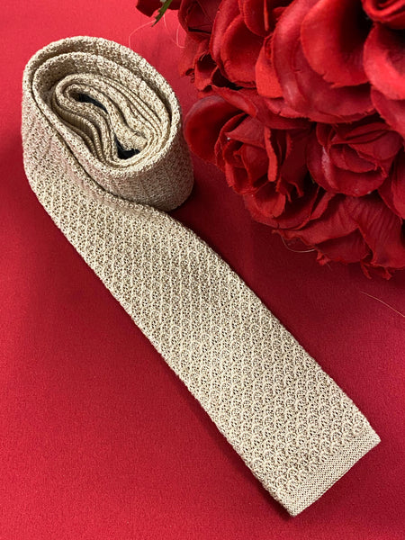 „Vintage Strickkrawatte beige auf rotem Hintergrund dekorativ drapiert“