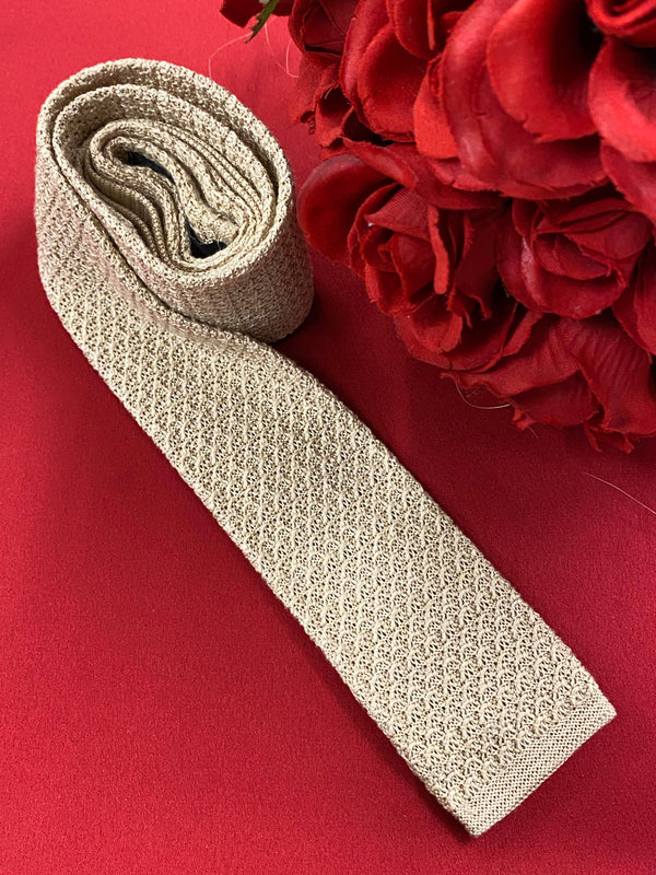 „Vintage Strickkrawatte beige auf rotem Hintergrund dekorativ drapiert“