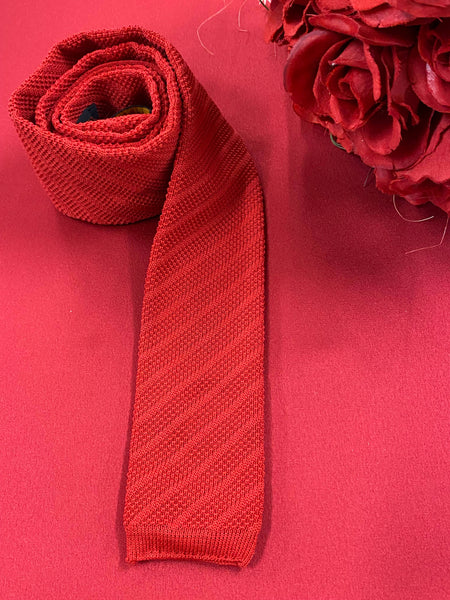 „Vintage Strickkrawatte rot von Henry John auf rotem Hintergrund dekorativ gelegt“