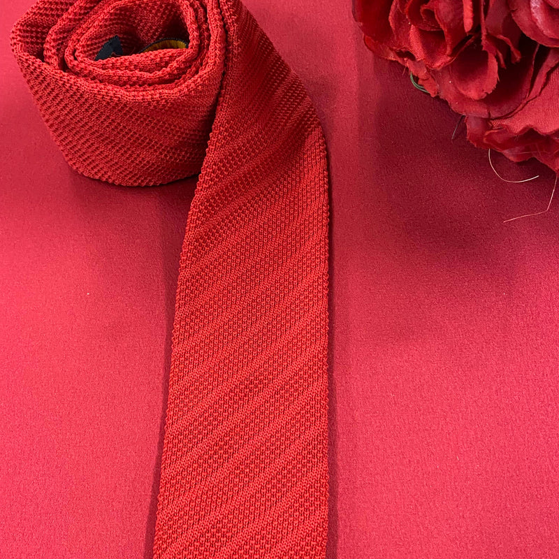 „Vintage Strickkrawatte rot von Henry John auf rotem Hintergrund dekorativ gelegt“