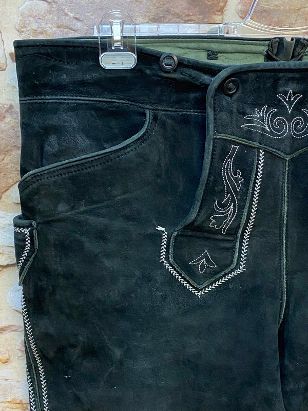„Detailaufnahme schwarze Kniebund Trachtenlederhose mit traditioneller heller Stickerei am Latz“