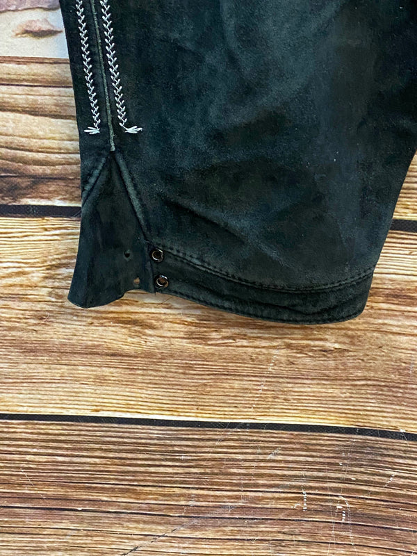 „Beinabschluss einer schwarzen Vintage Lederhose mit Knöpfen und dekorativer Trachtenstickerei“
