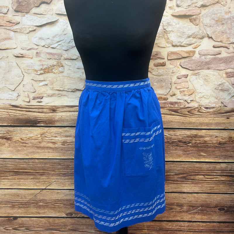 „Königsblaue Vintage-Trachtenschürze aus Baumwolle mit hellen Stickbordüren, 1970er, Frontansicht am Mannequin.“