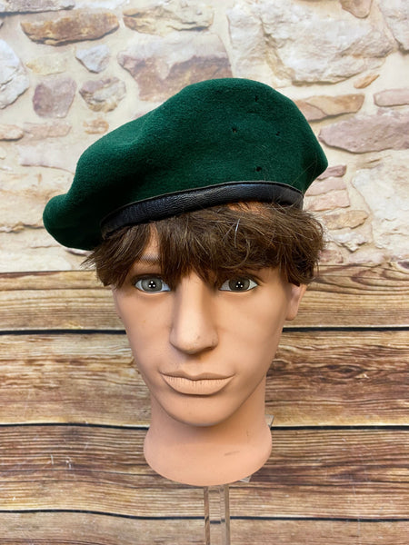 „Grünes Vintage Uniform-Barett Größe 59 mit schwarzem Rand auf Schaufensterkopf“