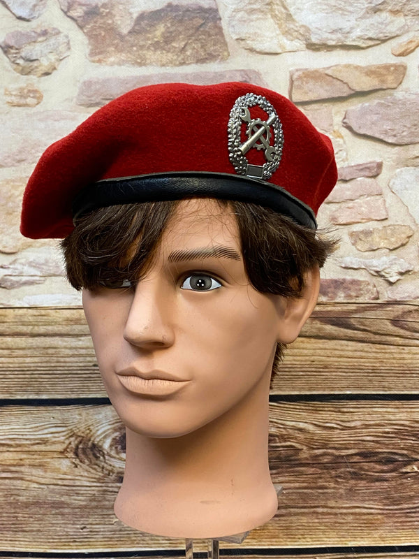 „Rotes Vintage Uniform-Barett Größe 60 mit schwarzem Rand und Metallabzeichen auf Schaufensterkopf“