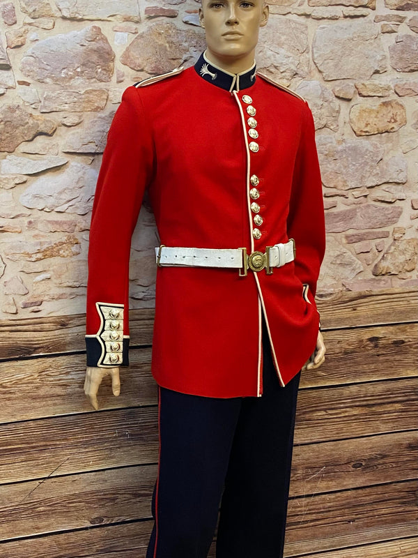 Rote Uniformjacke der Welsh Guards mit goldenen Knöpfen, schwarzer Hose mit rotem Streifen, Hosenträgern und weißem Gürtel mit messingfarbener Schnalle.