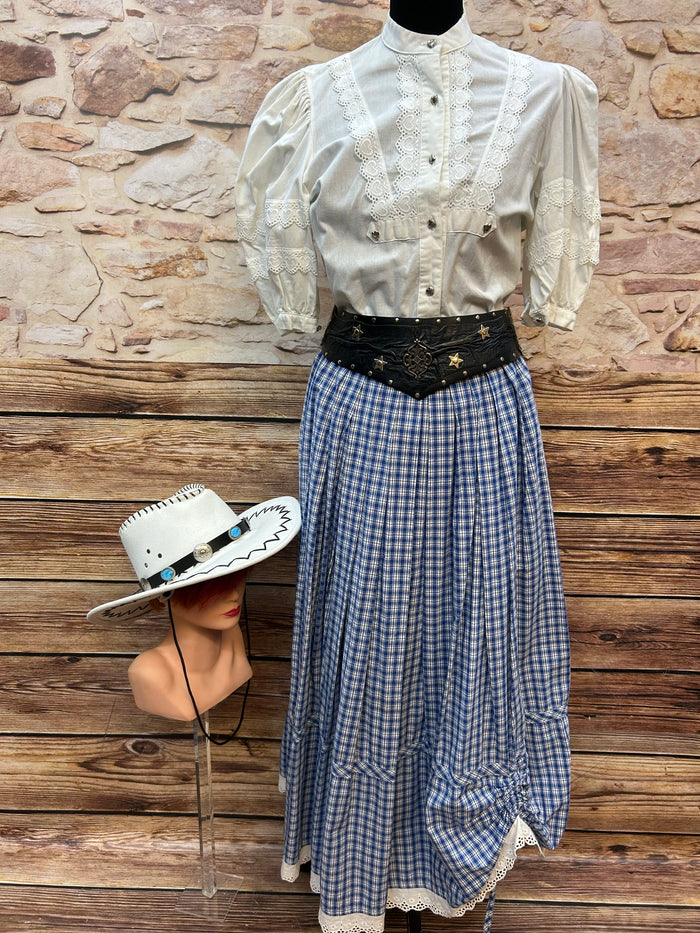 Western Damen-Kostüm in Größe 36/M mit weißer Herzbluse, blau kariertem Rock mit Spitze, schwarzem Western-Gürtel und weißem Cowboyhut mit türkisen Details.