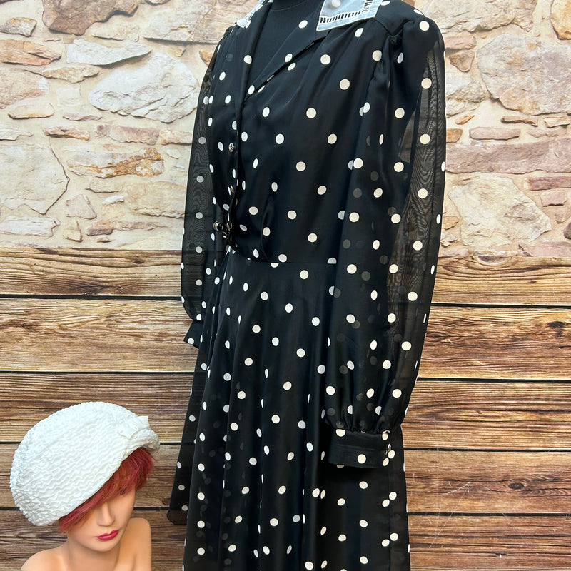 Vintage schwarzes Chiffonkleid mit weißen Tupfen, transparenten Puffärmeln und Hemdblusenkragen, dazu cremeweißer Cloche-Hut
