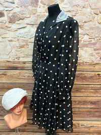 Vintage schwarzes Chiffonkleid mit weißen Tupfen, transparenten Puffärmeln und Hemdblusenkragen, dazu cremeweißer Cloche-Hut