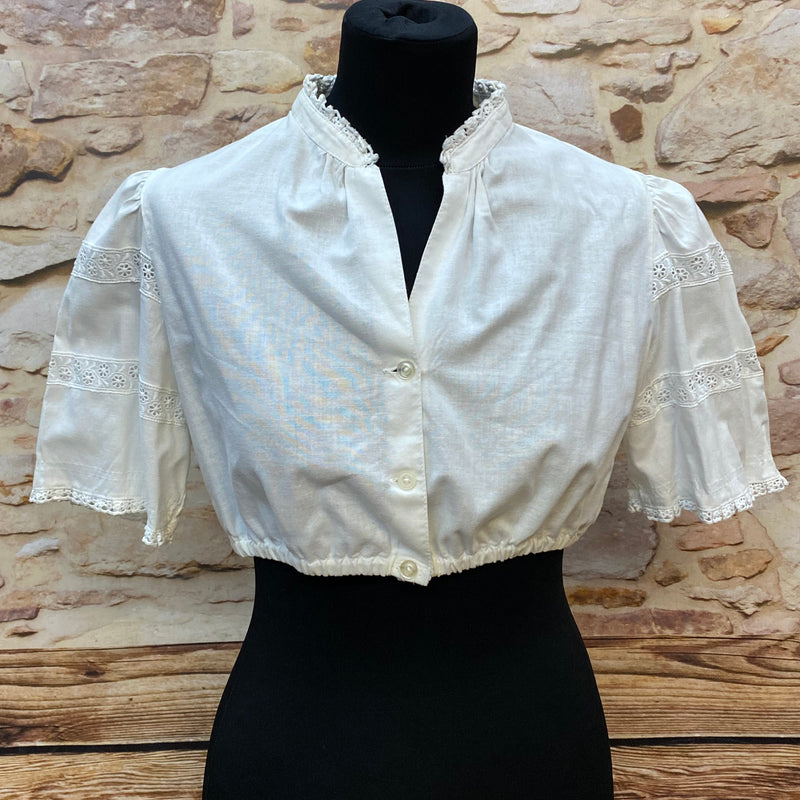 „Weiße Vintage-Dirndlbluse Hagro, Größe 42, mit Stehkragen, Knopfleiste und Spitzenborten an halblangen Puffärmeln, 1980er Jahre.“