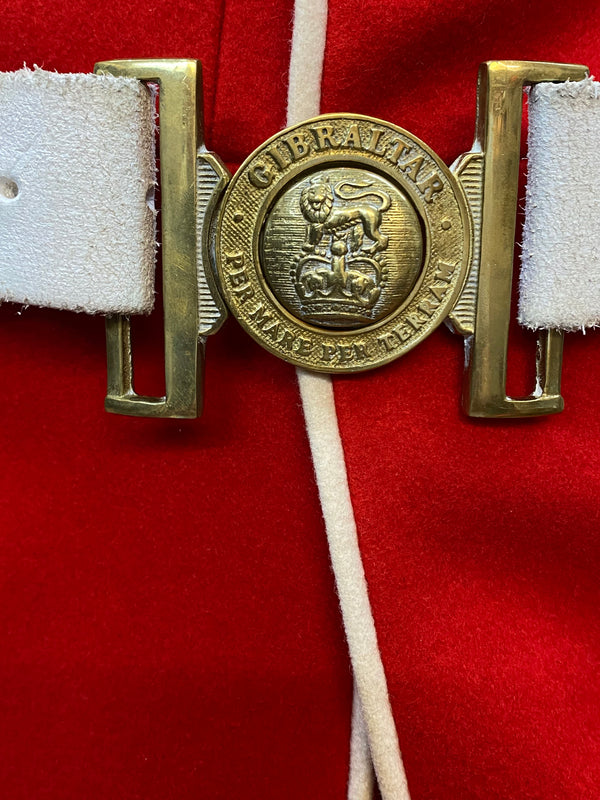 Messingfarbene Gürtelschnalle der Welsh Guards mit Aufschrift „Gibraltar“ und Löwenemblem auf weißem Gürtel.