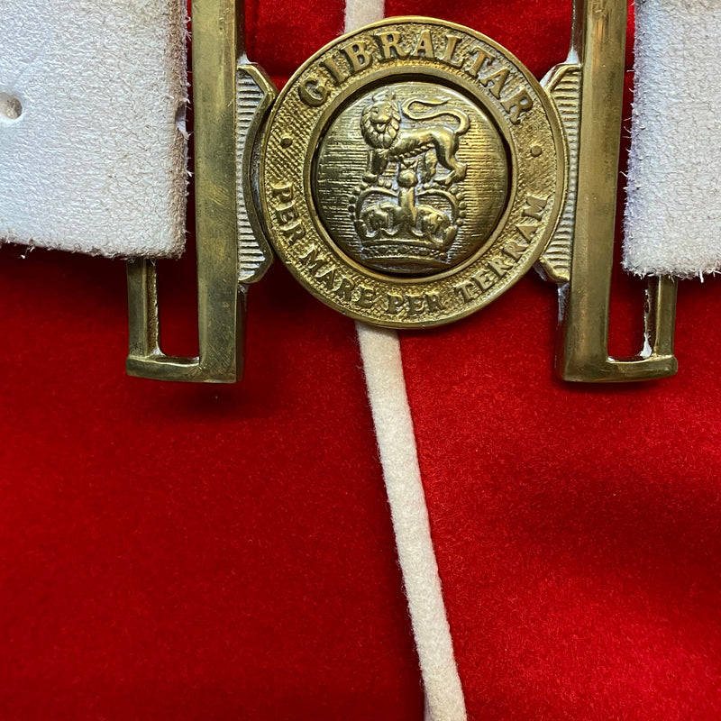 Messingfarbene Gürtelschnalle der Welsh Guards mit Aufschrift „Gibraltar“ und Löwenemblem auf weißem Gürtel.