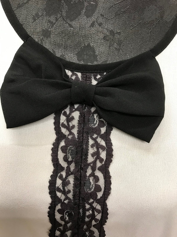 Detailaufnahme der Schleife und Spitzenverzierung am Kragen der Bluse.