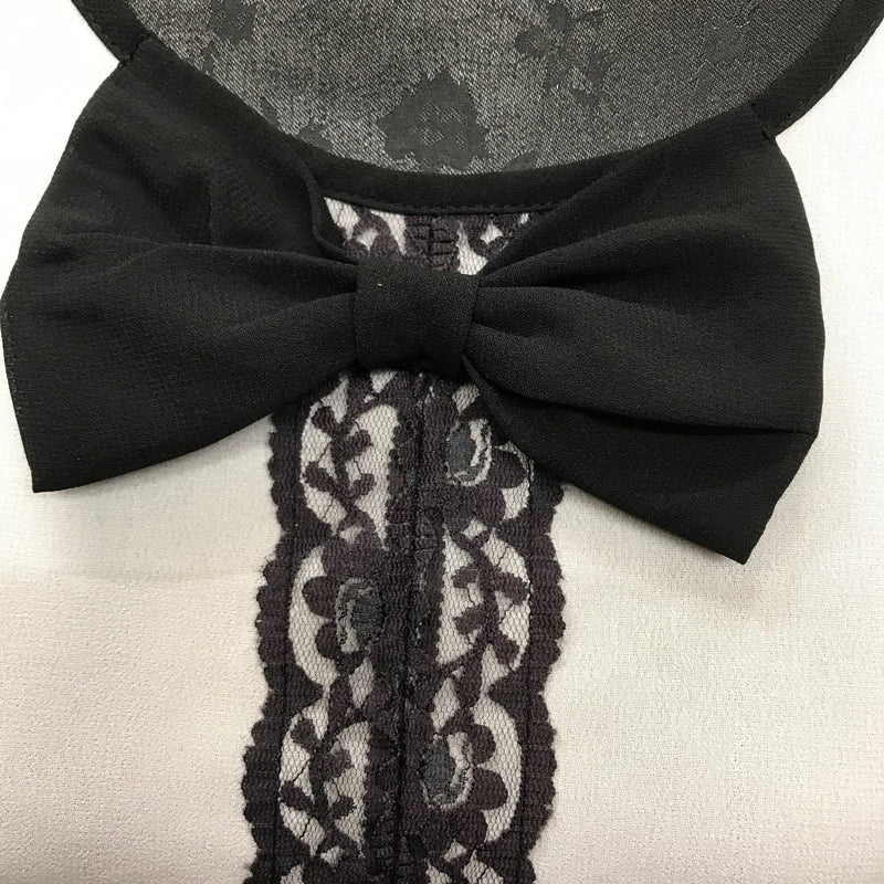 Detailaufnahme der Schleife und Spitzenverzierung am Kragen der Bluse.
