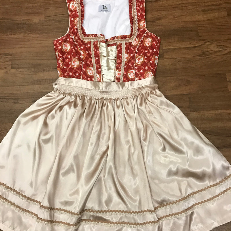 Dirndl flach gelegt mit gebundener beiger Schürze, Vorderansicht.
