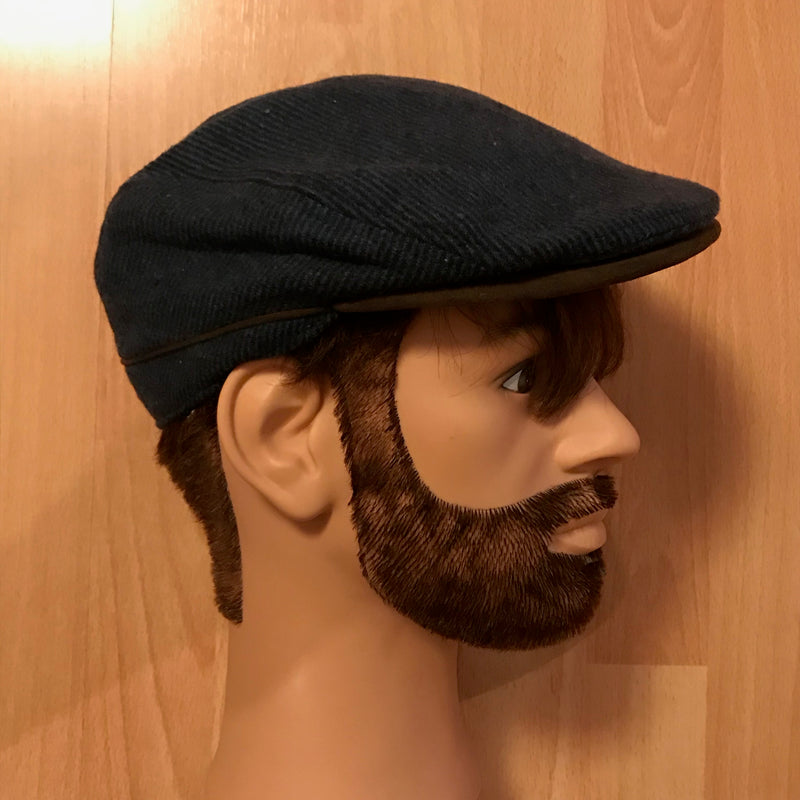Seitenansicht einer dunkelblauen Schiebermütze im 20er Jahre Stil auf einem Herren-Schaufensterkopf.