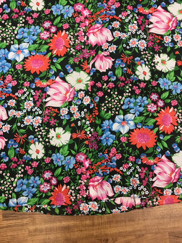 Detailaufnahme des farbigen Blumenmusters des Vintage-Maxirocks auf schwarzem Grund