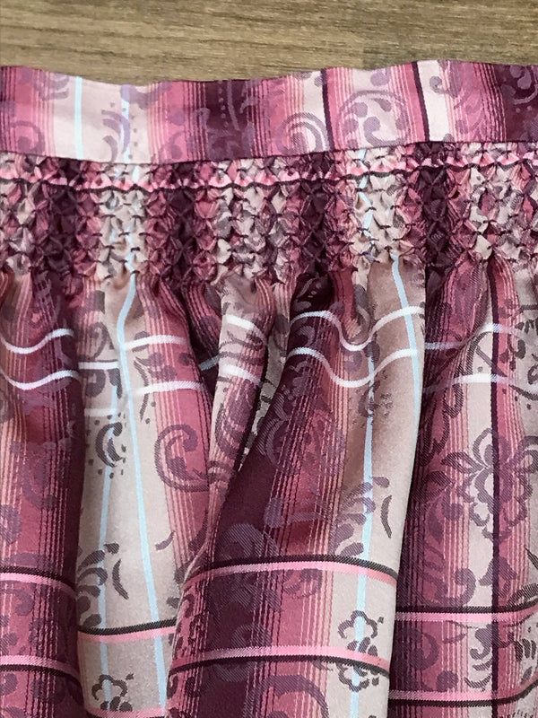 „Gesmockter Bund und florales Streifen-Dessins einer rosa Dirndl-Schürze“