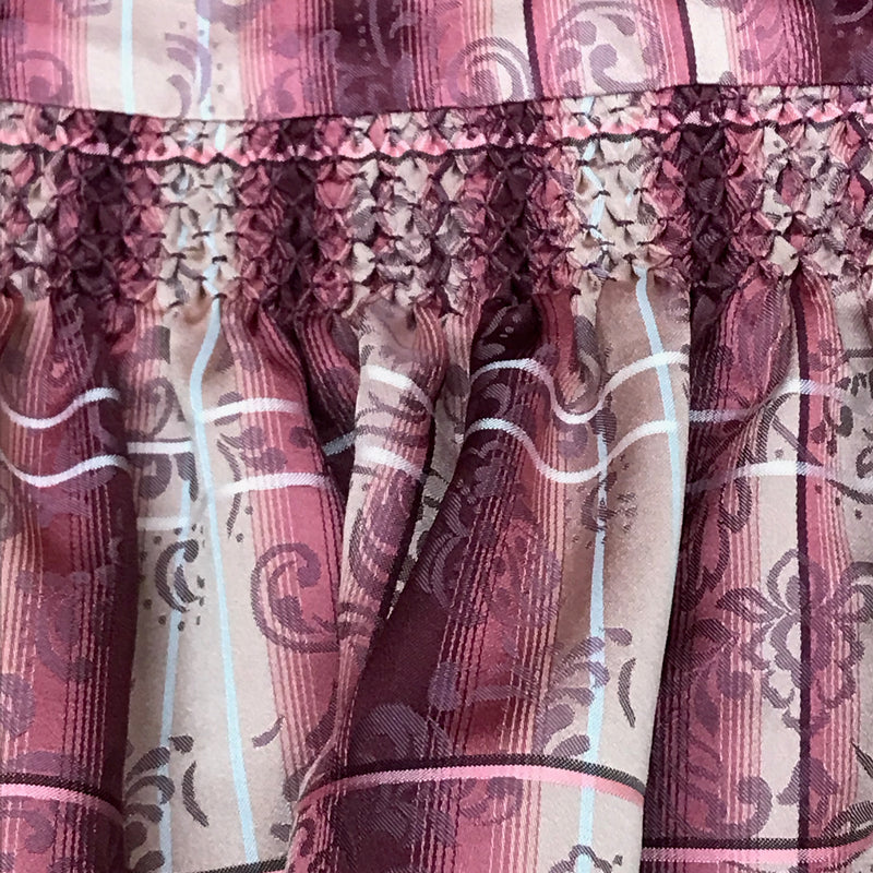 „Gesmockter Bund und florales Streifen-Dessins einer rosa Dirndl-Schürze“