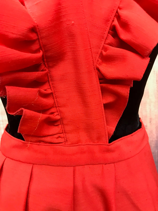 „Detailaufnahme rotes Vintage Kleid mit Volants und strukturierter Stoffoberfläche“
