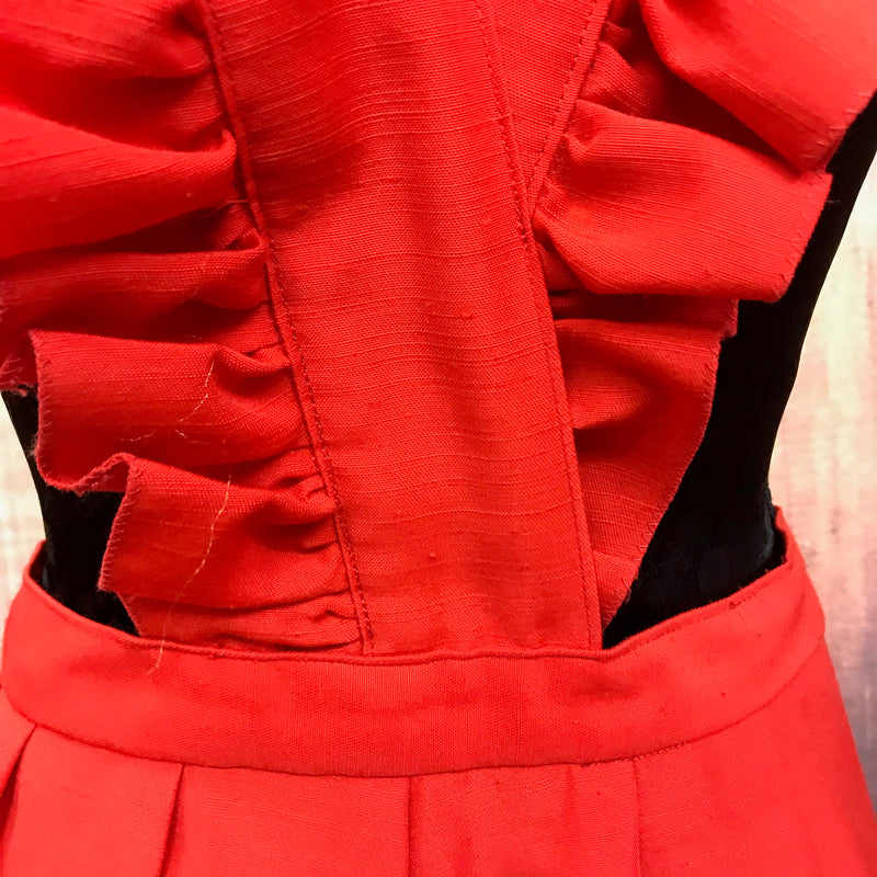 „Detailaufnahme rotes Vintage Kleid mit Volants und strukturierter Stoffoberfläche“