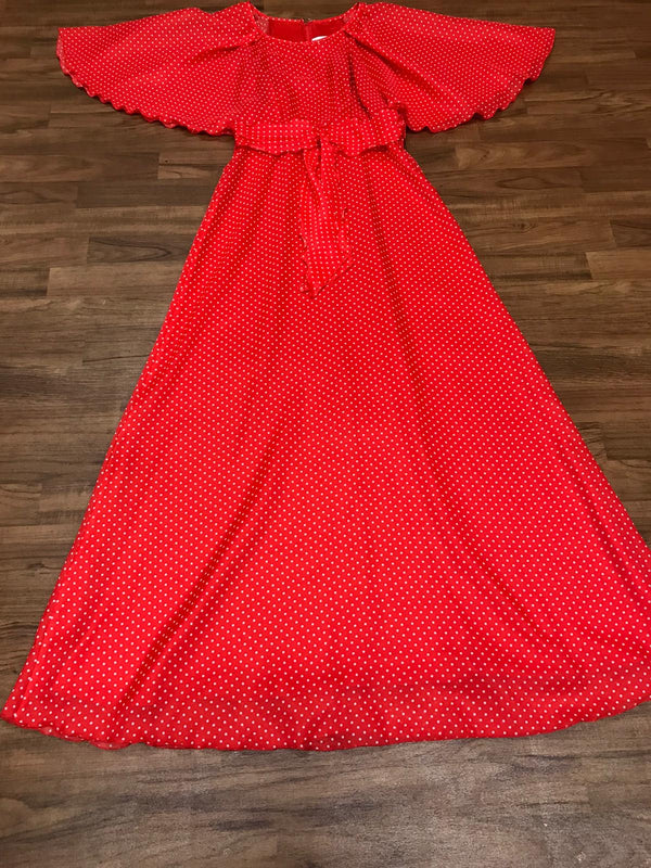 Kleid flach liegend: weite Cape-Ärmel, Bindegürtel und langer, schwingender Rock.