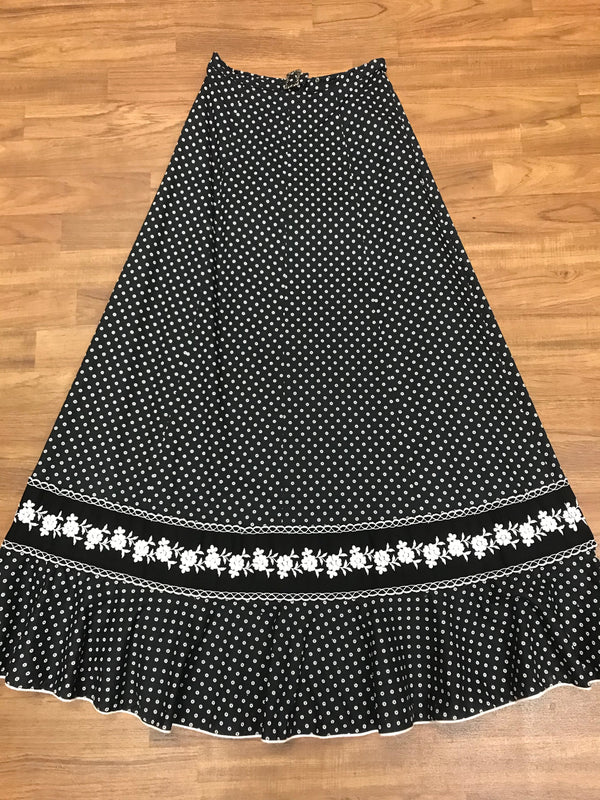 Schwarzer 70er-Vintage-Maxirock mit weißem Blümchenprint, floraler Bordüre und Volant-Saum – flachgelegt