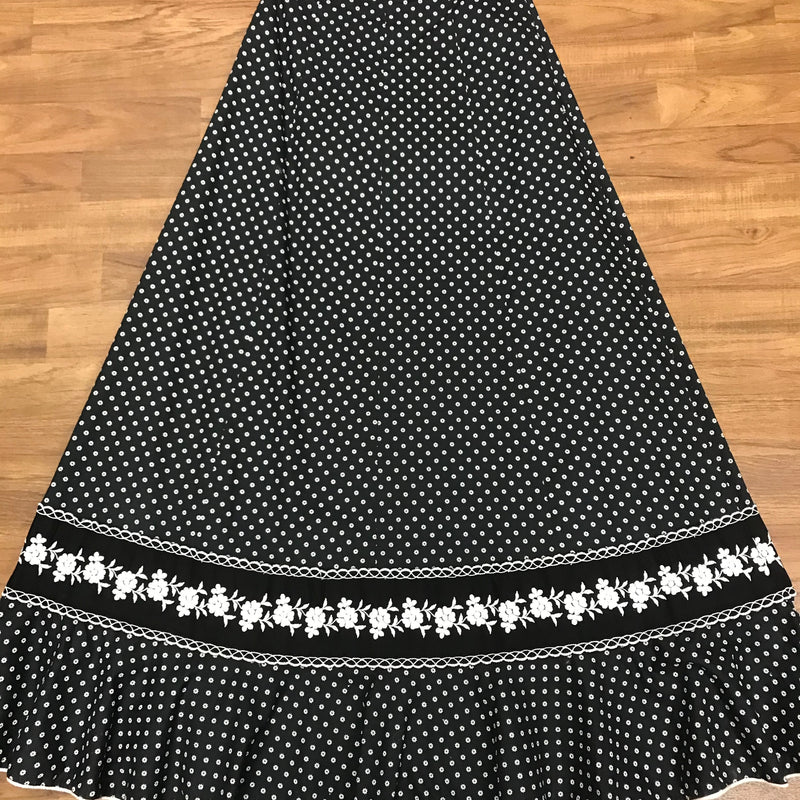 Schwarzer 70er-Vintage-Maxirock mit weißem Blümchenprint, floraler Bordüre und Volant-Saum – flachgelegt