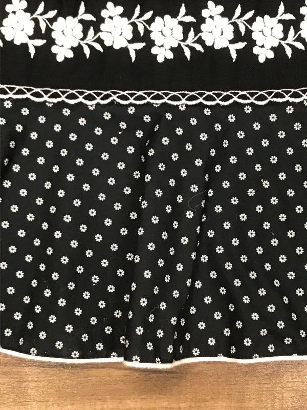 Detail der floralen Bordüre und des Volant-Saums am 70er-Vintage-Rock in Schwarz-Weiß