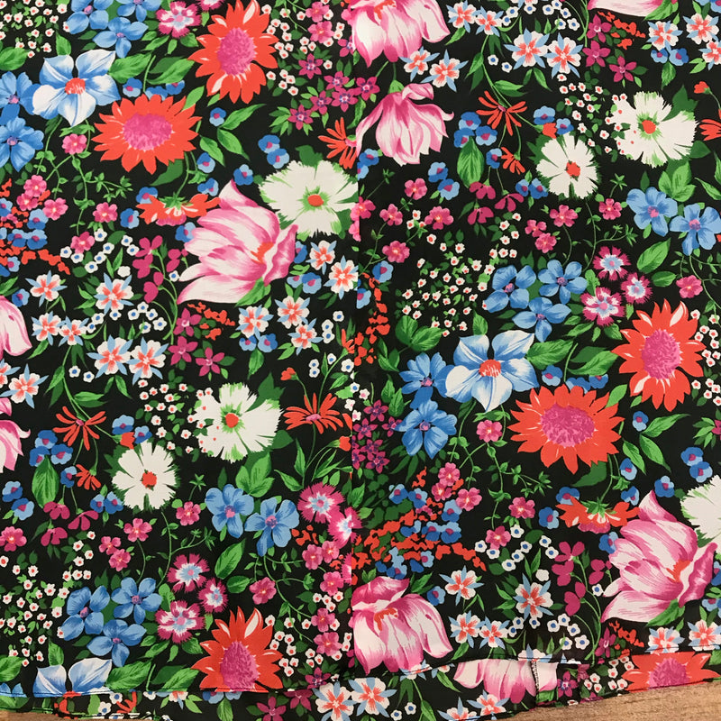 „Detailansicht floraler Vintage Rock mit buntem Blumenmuster auf schwarzem Stoff“