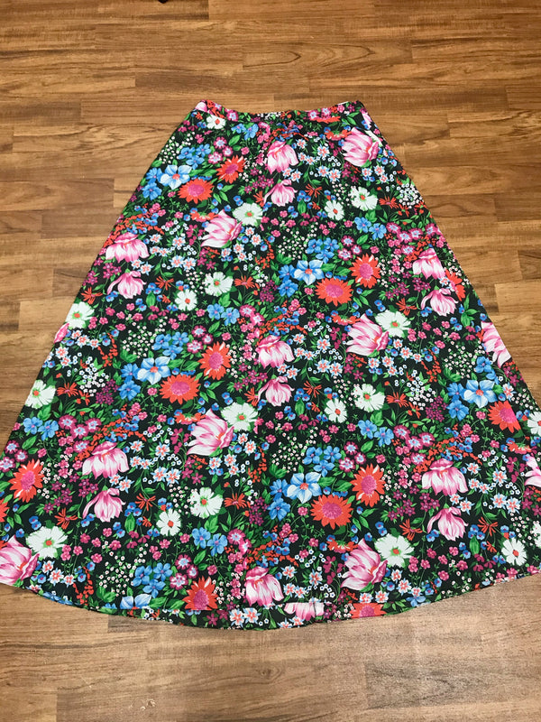 „Vintage Maxirock schwarz mit buntem Blumenprint ausgebreitet auf Holzboden“