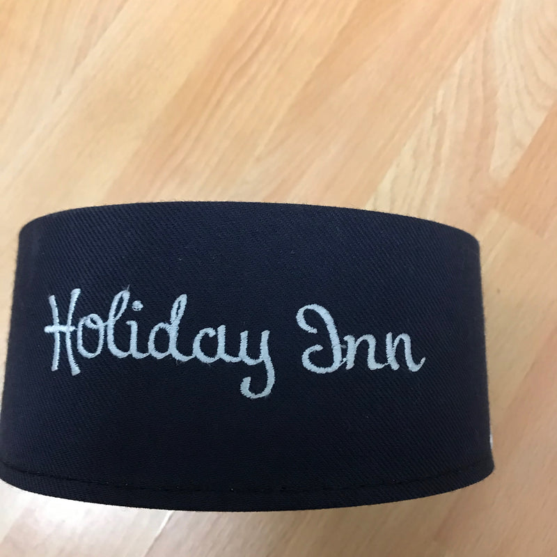 Frontansicht der Mütze mit weißer „Holiday Inn“-Stickerei auf dunkelblauem Stoff.
