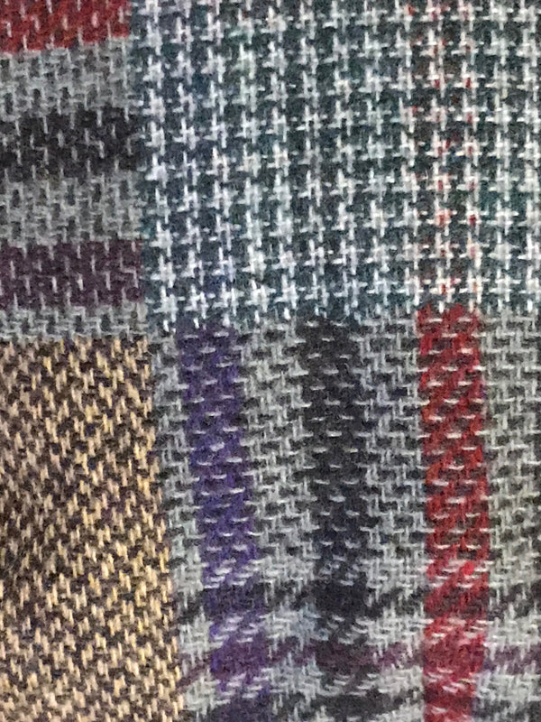 Detailaufnahme kariertes Patchwork-Muster der Vintage Schiebermütze, Wollmischung in Blau, Grau, Rot und Beige.