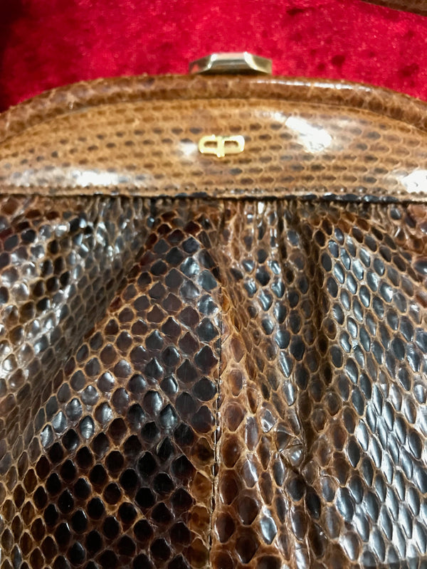 Rückseite der braunen Schlangenleder Handtasche mit goldfarbenem Rahmen.
