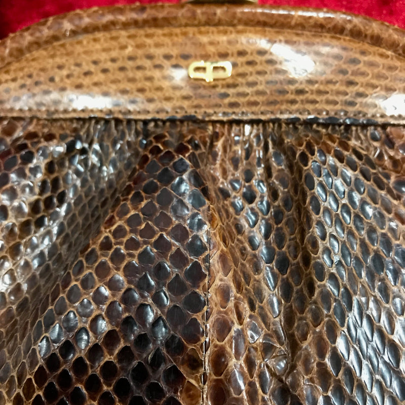 Rückseite der braunen Schlangenleder Handtasche mit goldfarbenem Rahmen.